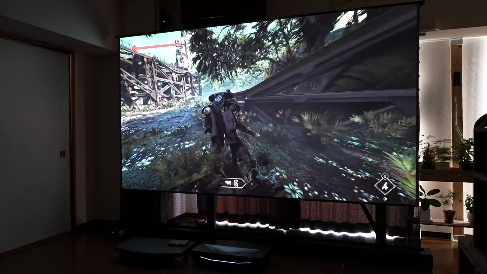 薄暗い部屋で暗いゲームシーンを投影した大画面。黒が深く沈んでいる