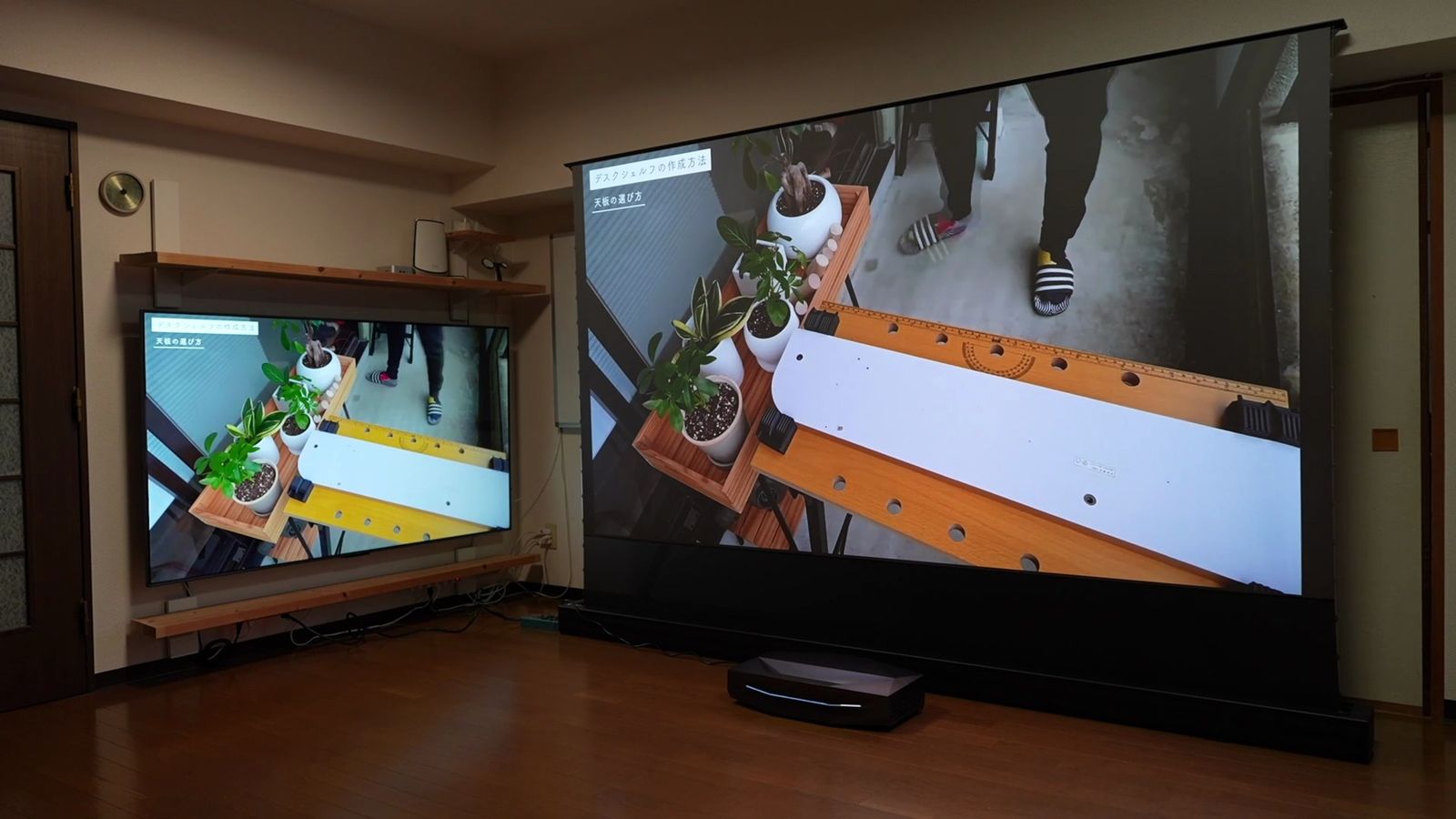 明るい部屋での投影。左の薄型テレビより大きく映る大画面