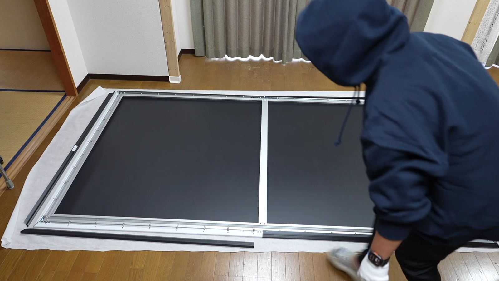 床に広げた120インチのフレームと人の大きさの対比