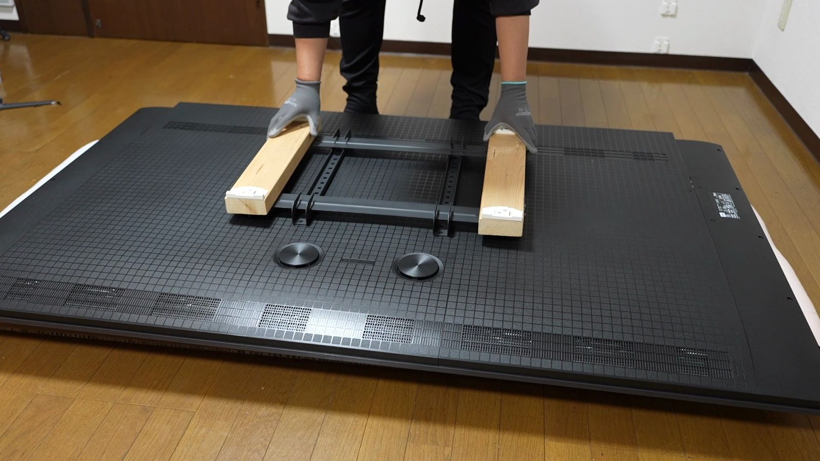 うつ伏せにしたC6Kの背面に壁面固定用の木材を取り付けているところ