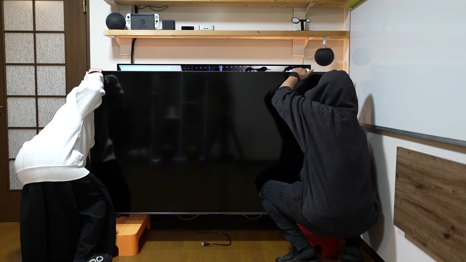 2人がかりで75インチ本体を設置しているところ