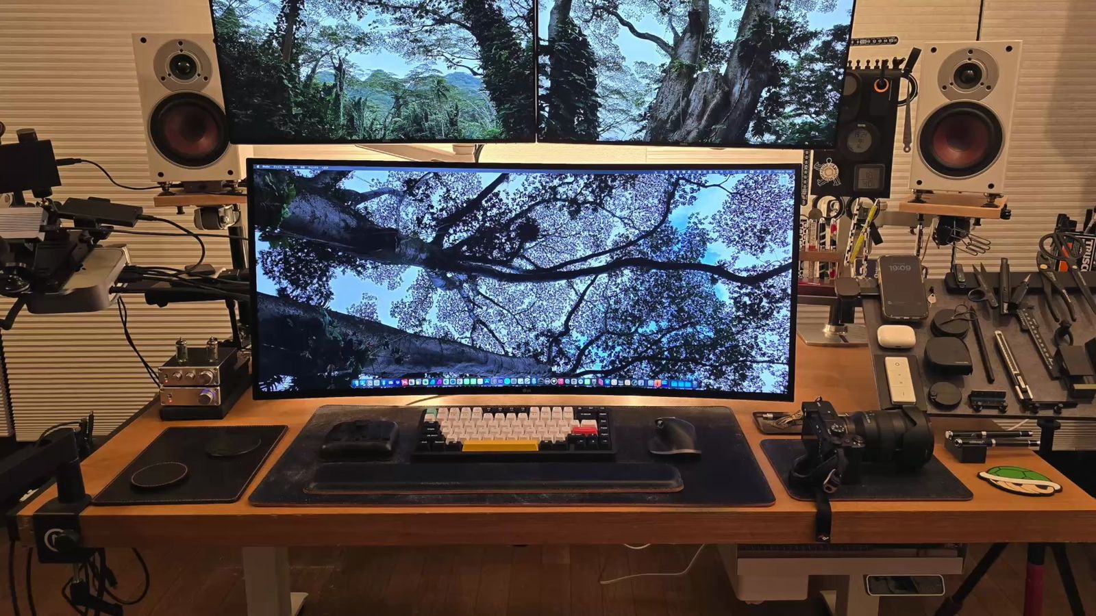 ウルトラワイドモニターとキーボードで埋まった夜のデスク天板