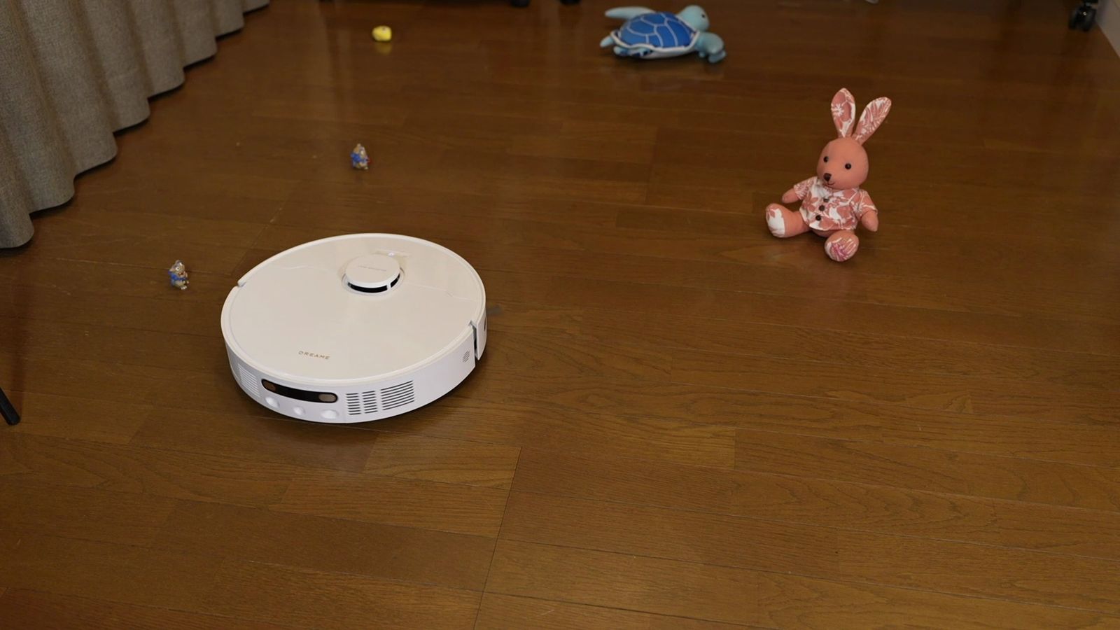 床のおもちゃの手前に立つ本体。前面に障害物検知センサーの窓が並ぶ