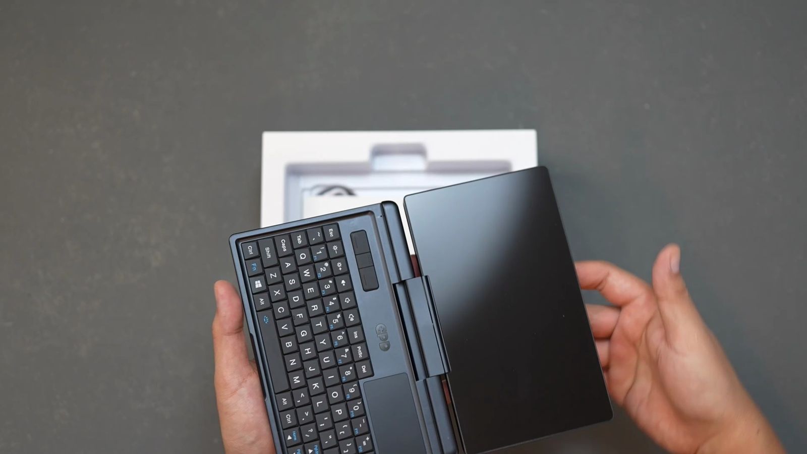 GPDの小型2in1ノートPCを両手で開いたところ。画面側は消灯している