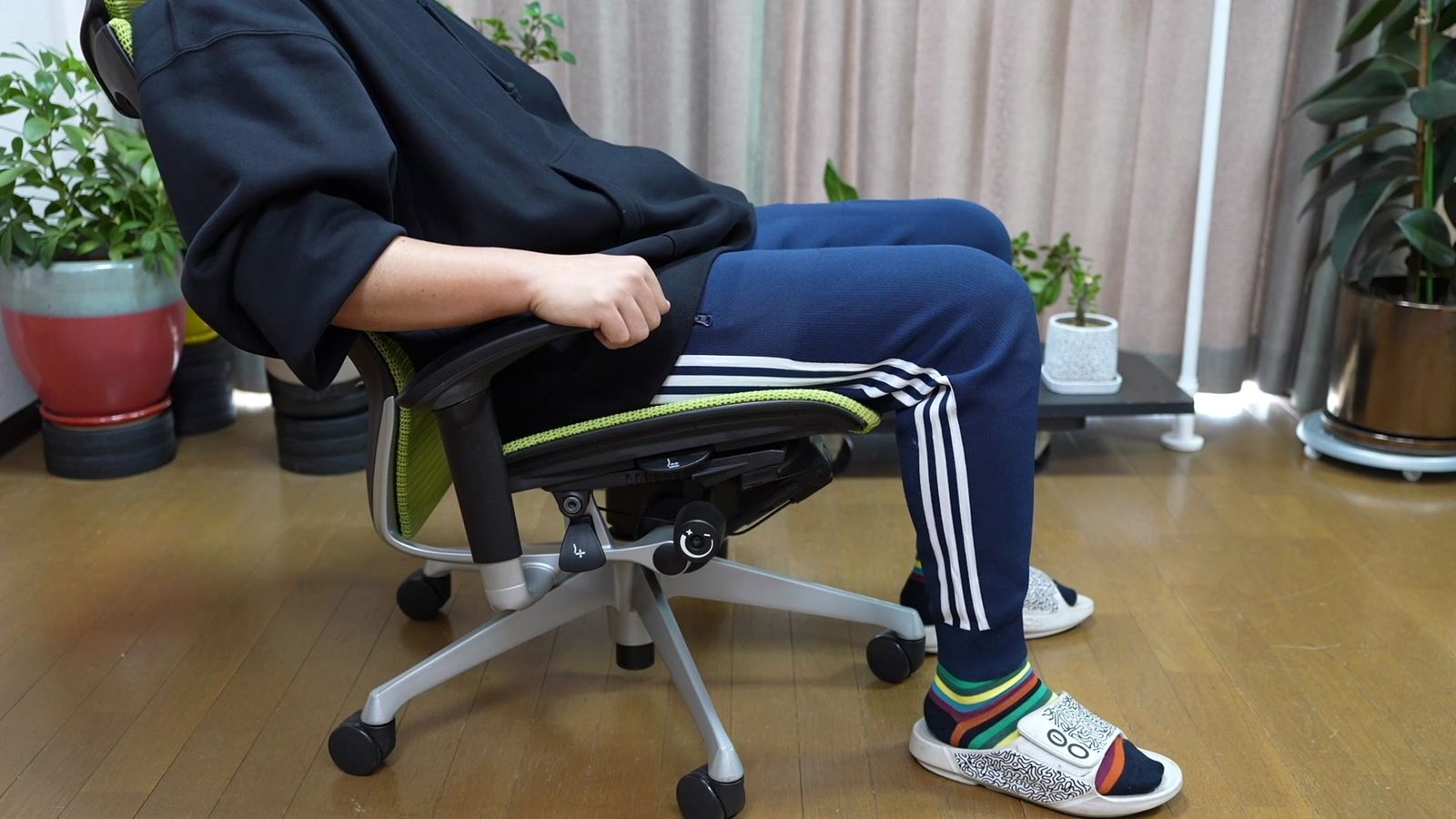 緑メッシュのオフィスチェアに座り、座面ごと後傾している横からのカット