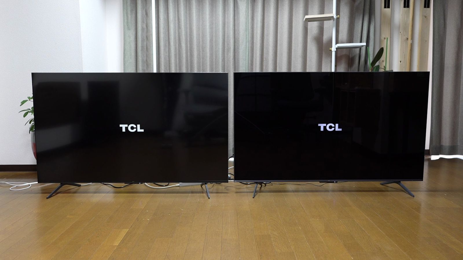 明るい室内に並べた2台のTCLテレビ。どちらも黒画面にTCLロゴを表示し、左側の画面には窓とカーテンの映り込みが白く広がり、右側は映り込みが少ない