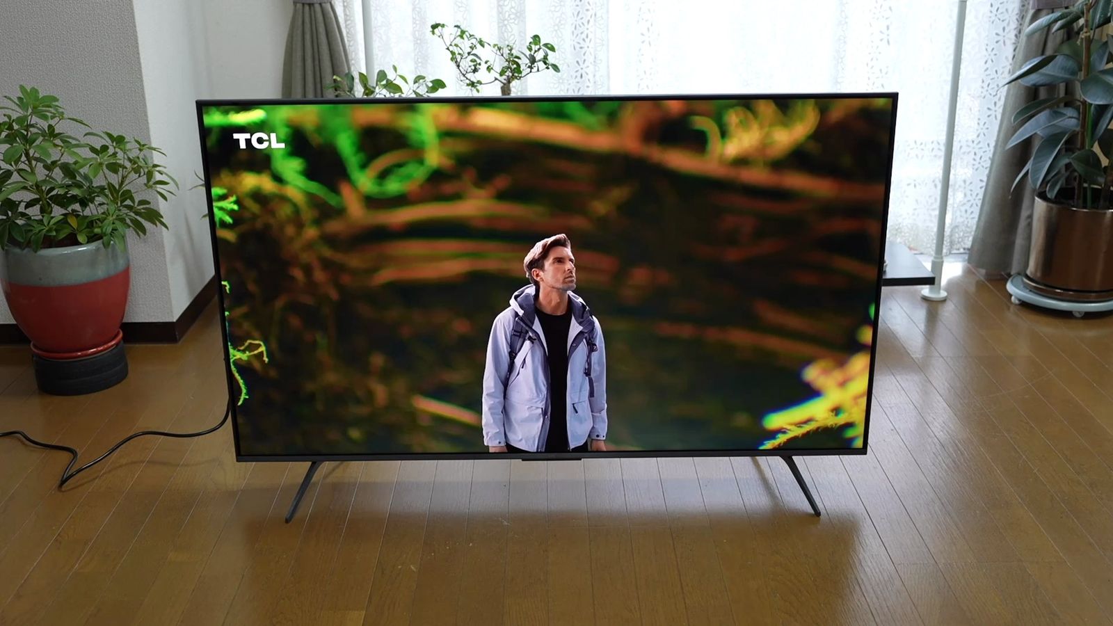 明るい室内に床置きした55型TCLテレビを斜めから見たカット。画面を囲むベゼルが細く、本体側面の薄さが分かる