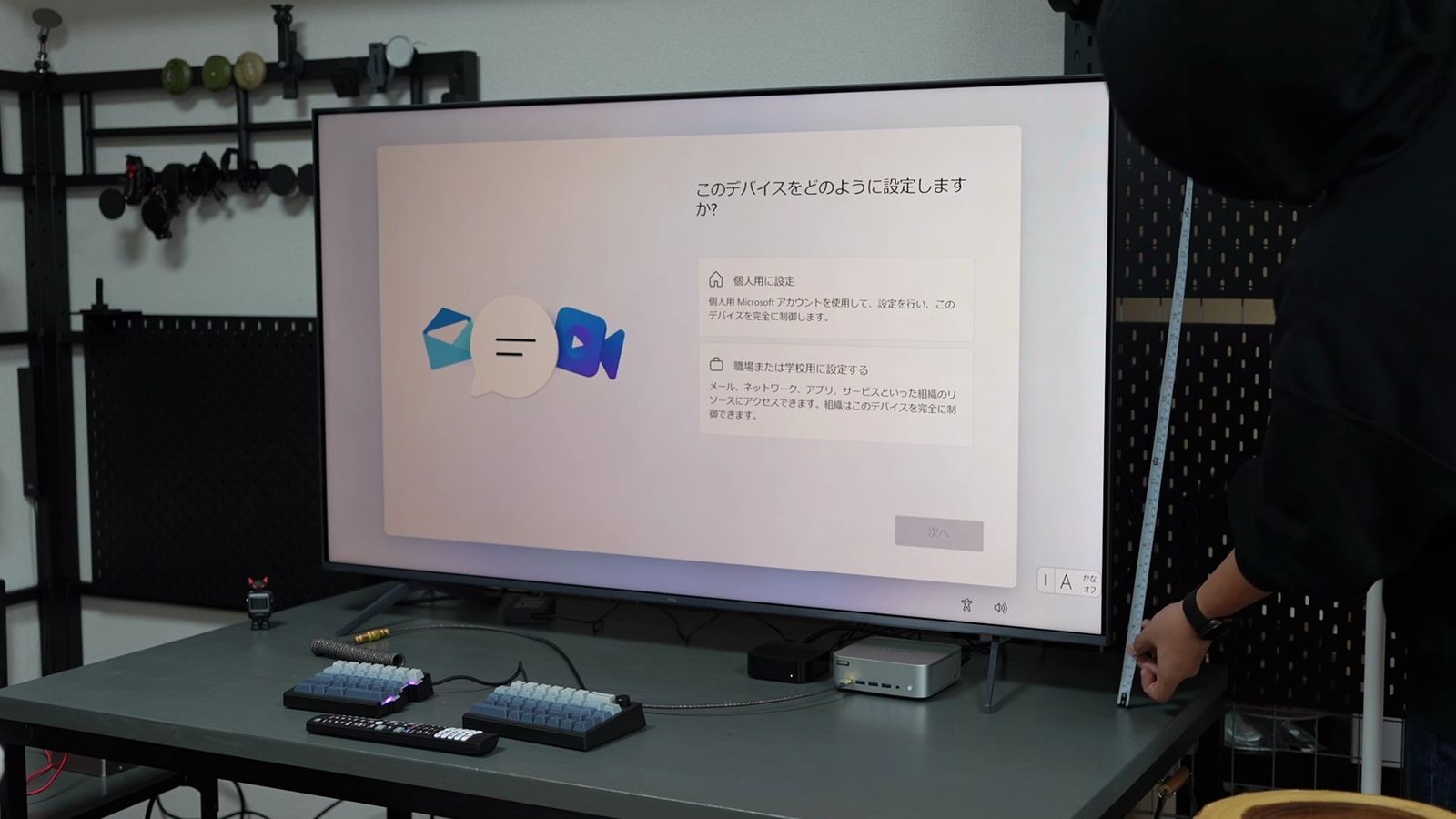 付属スタンドでデスクに置いた55型テレビ。画面の下端がデスク面から浮いており、右側で手が寸法を測っている