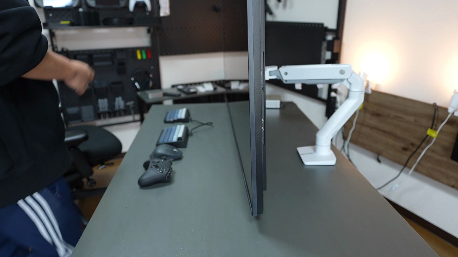 モニターアームで支えた55型テレビを真横から見たカット。画面の下端がデスク面のすぐ上にあり、右にエルゴトロン製の白いアームとデスククランプが見える