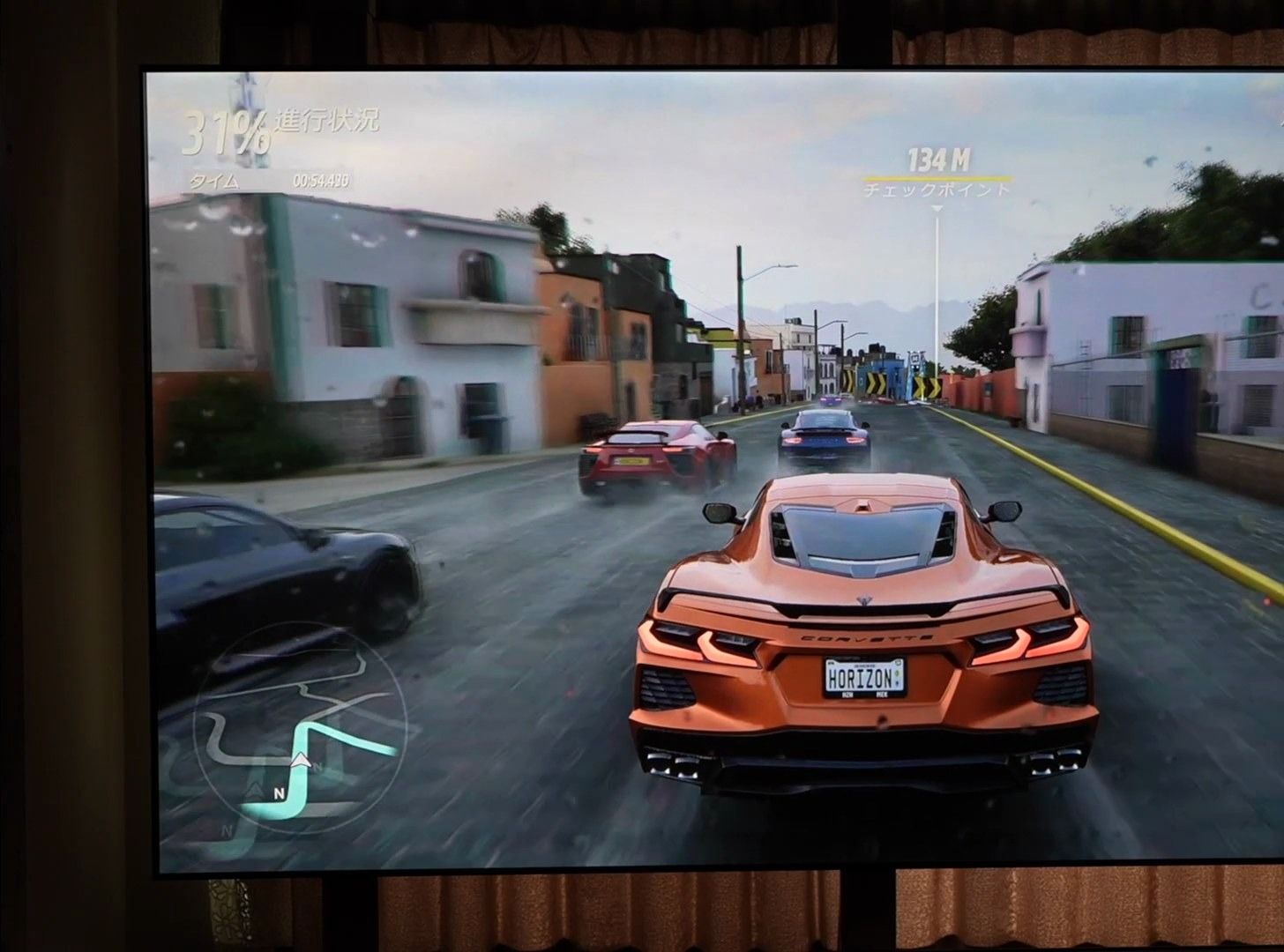 暗い部屋でALRスクリーンに投影したレースゲーム画面。黒が沈み有機ELのような発色