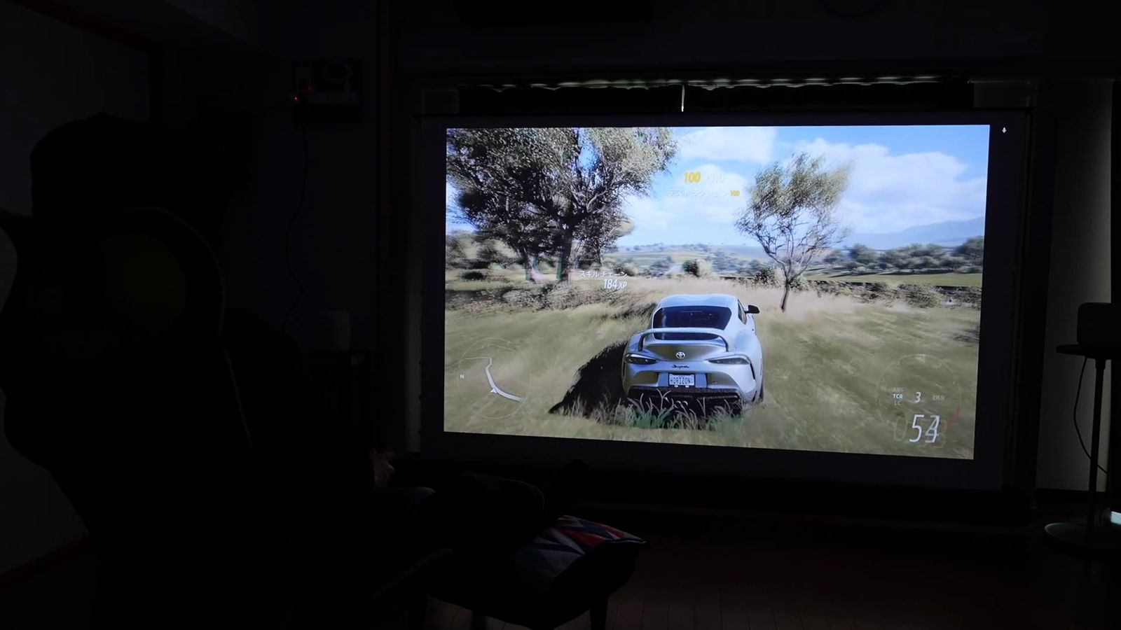 大画面に投影したレースゲームのプレイ画面