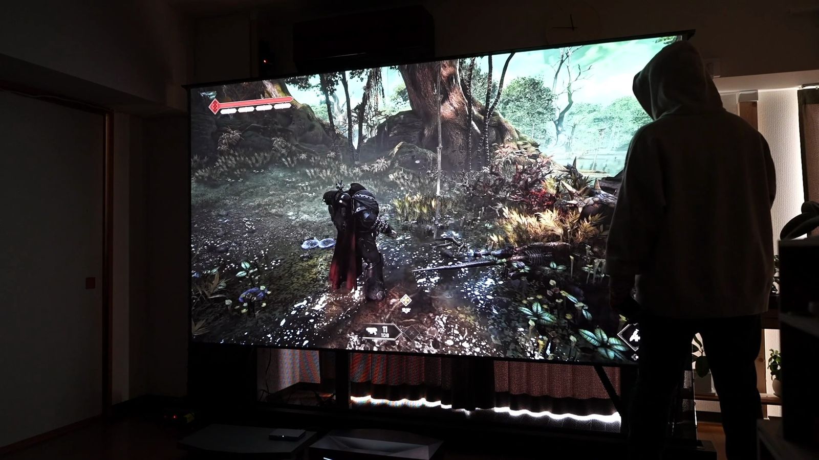 大画面に投影したゲームの横に人が立っているところ
