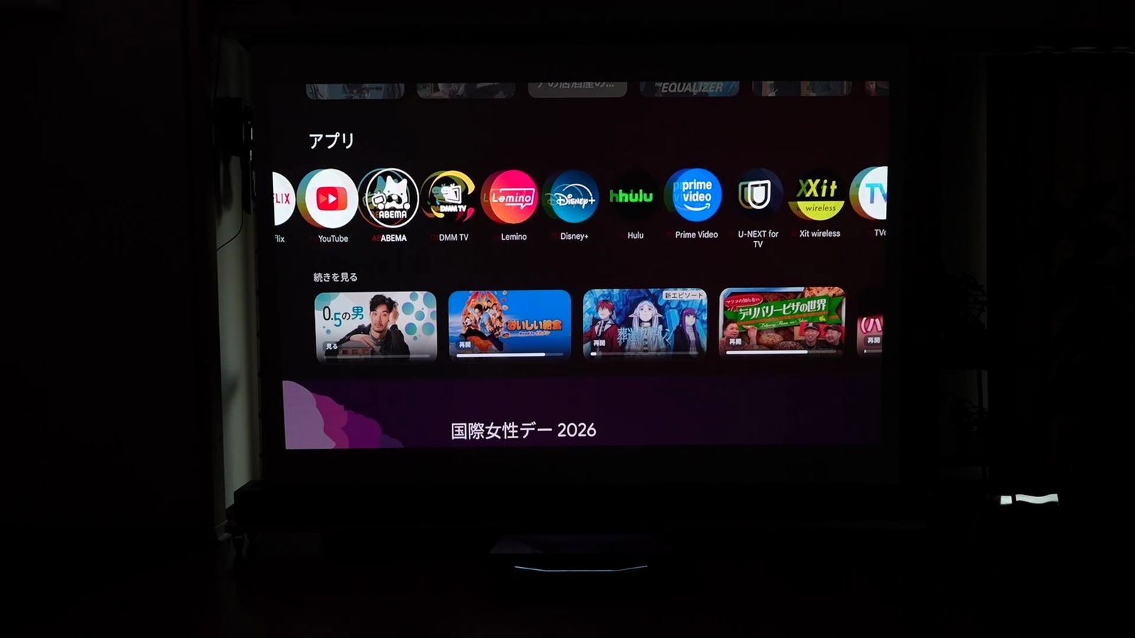 暗い部屋で投影したGoogle TVのホーム画面とアプリの一覧