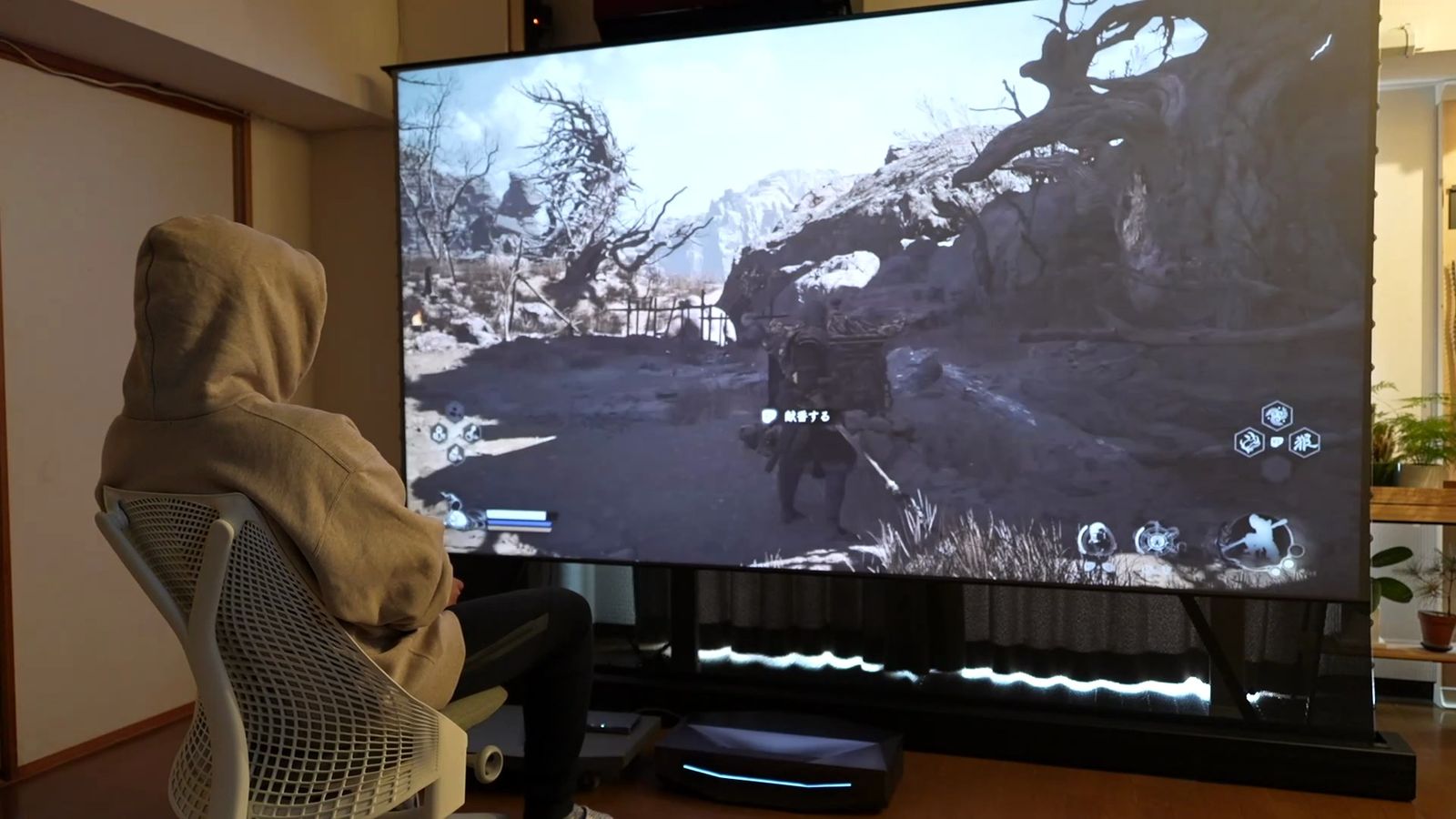 スクリーンの近くの椅子に座ってゲームをしているところ