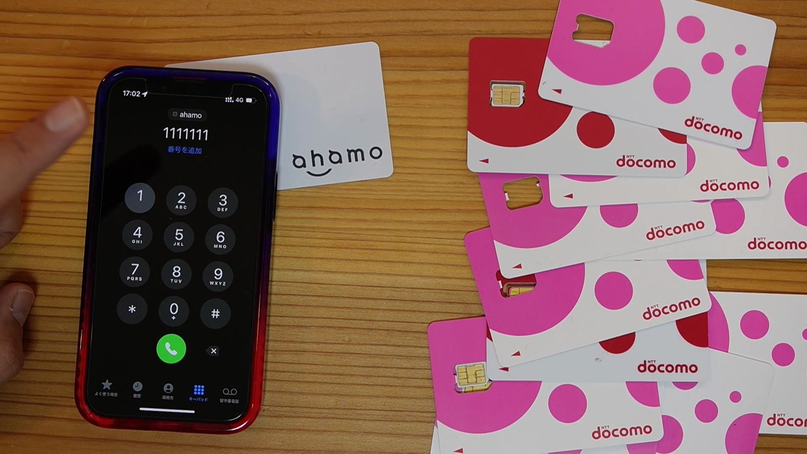 ahamoのSIMカードの横に置いたiPhoneの電話のキーパッド画面