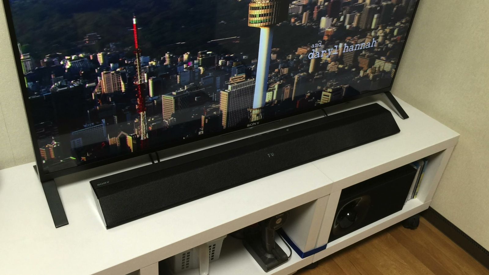 白いテレビ台に置いたテレビとサウンドバー