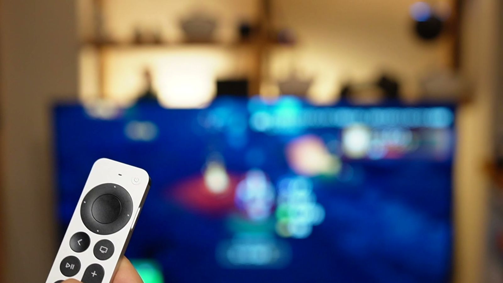テレビの前でApple TVのリモコンを持っているところ