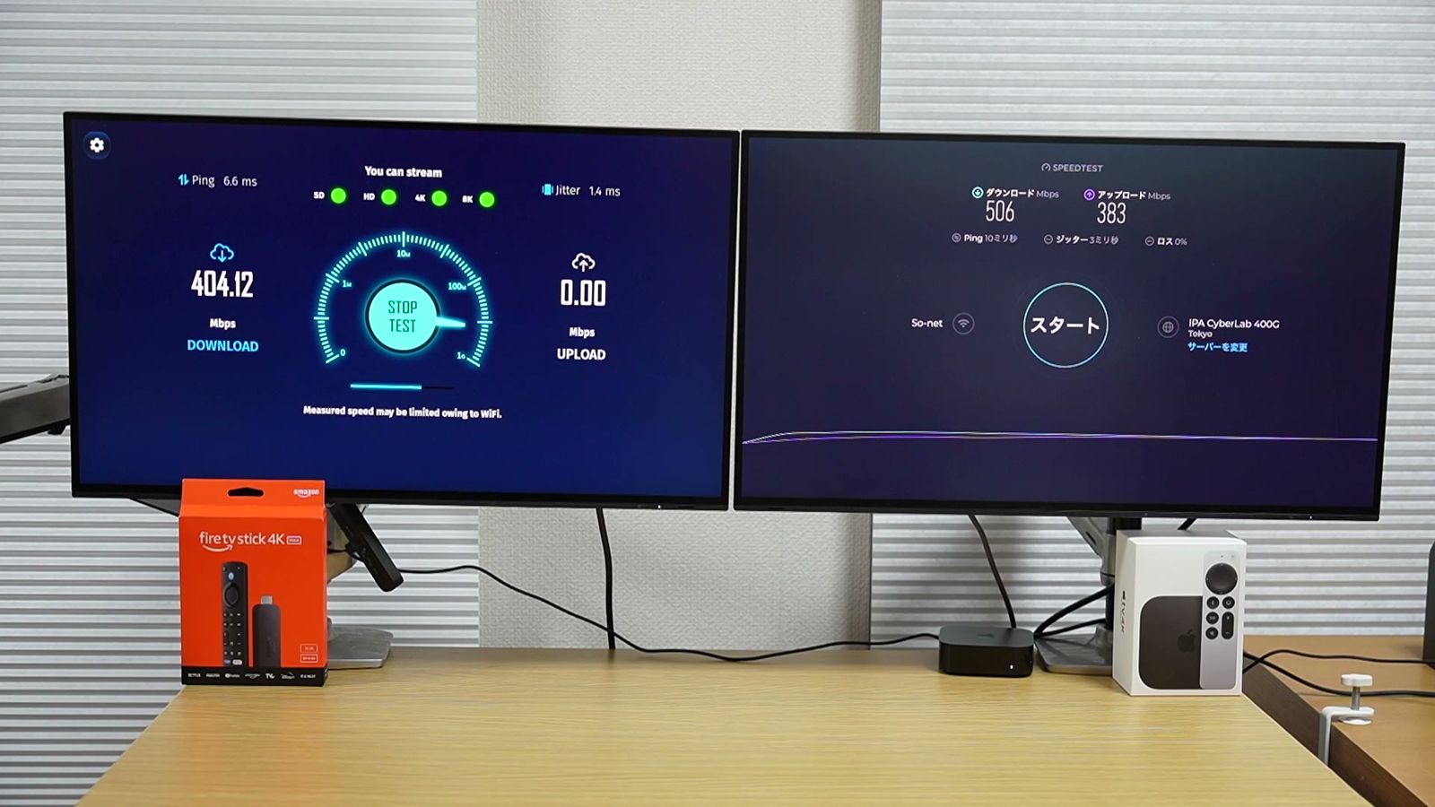 デスクのモニターの下に置いたFire TV Stickの箱と、Apple TV 4Kの箱と本体