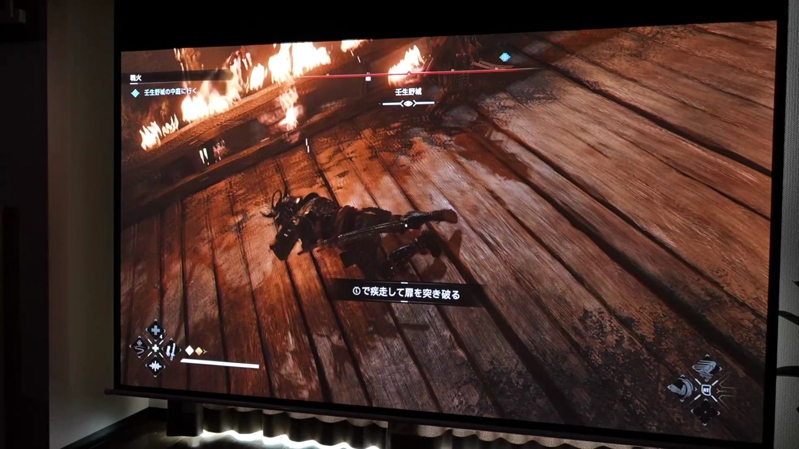暗い部屋でスクリーンに投影した、炎が上がるゲームの場面
