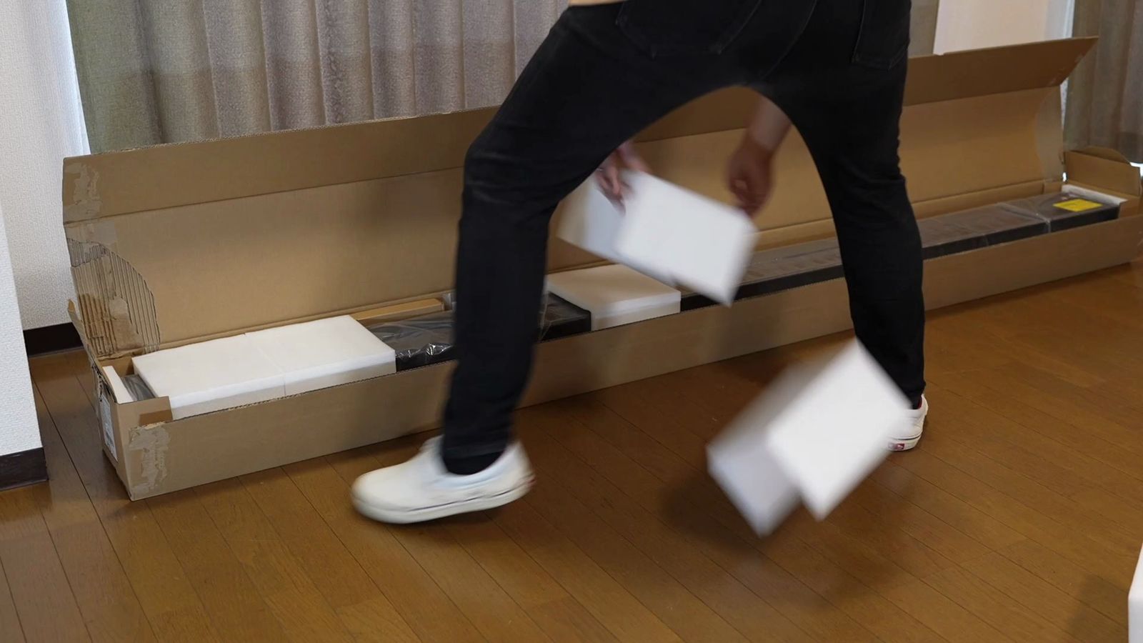 細長い箱から自立式スクリーンの本体を取り出しているところ