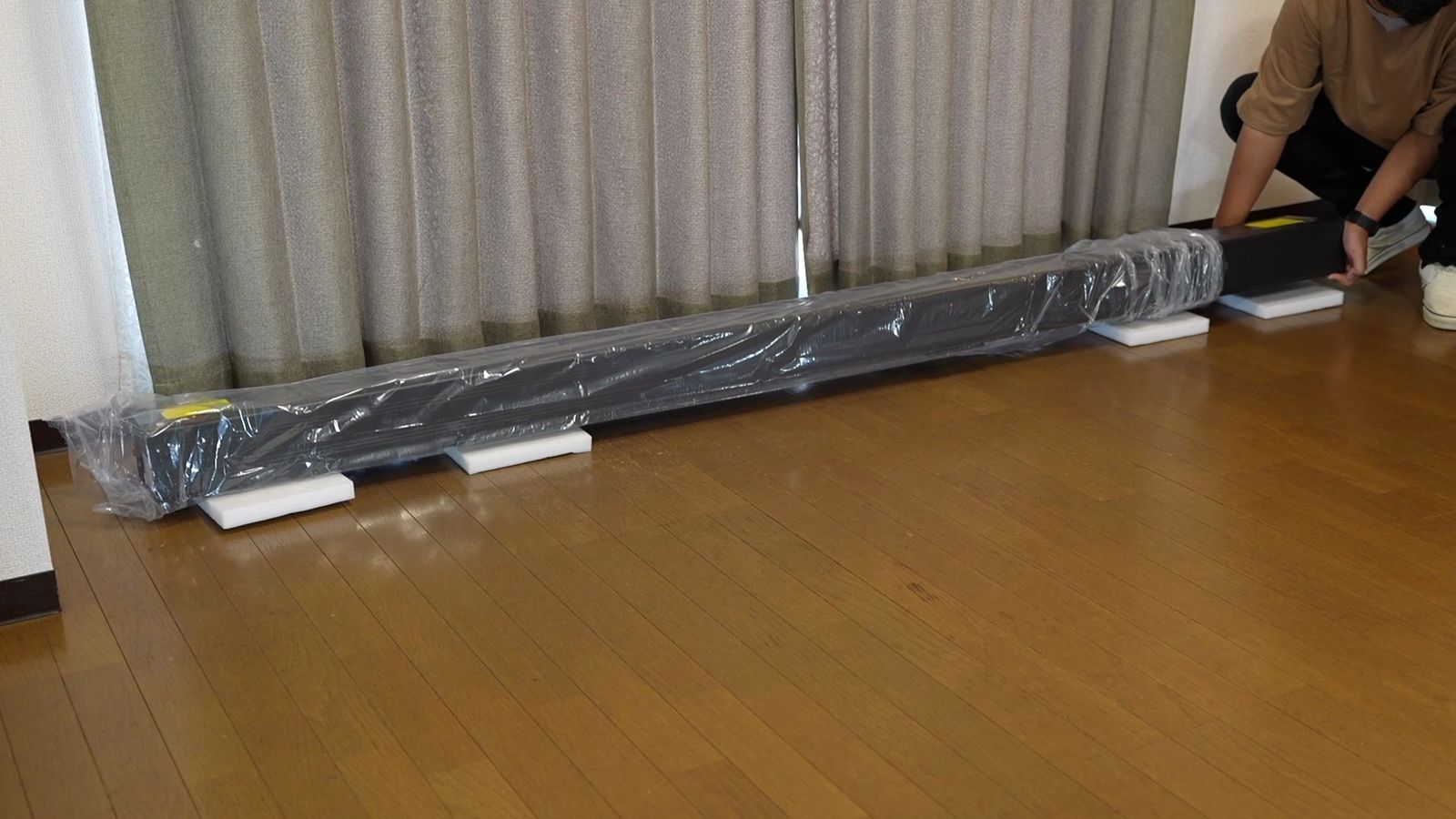 床に置いた、ビニールで梱包された長いスクリーンの本体
