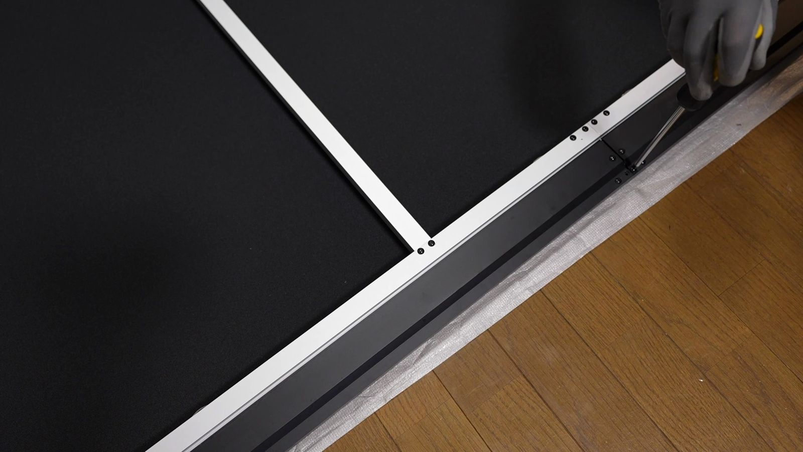 フレームの外側の部材を、工具を使って取り付けているところ