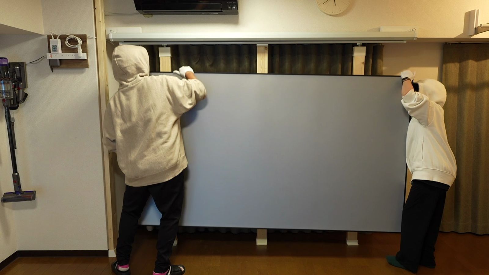 2人で柱にスクリーンを掛けているところ