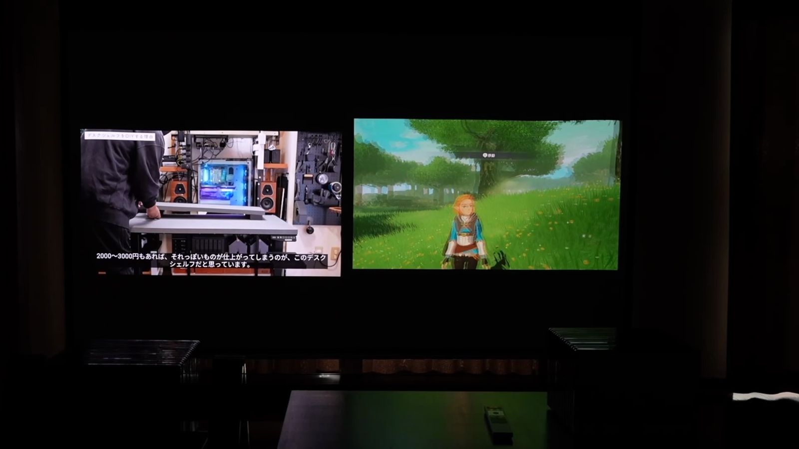 暗い部屋で小さいサイズに投影した2つの画面（左は動画、右はゲーム）