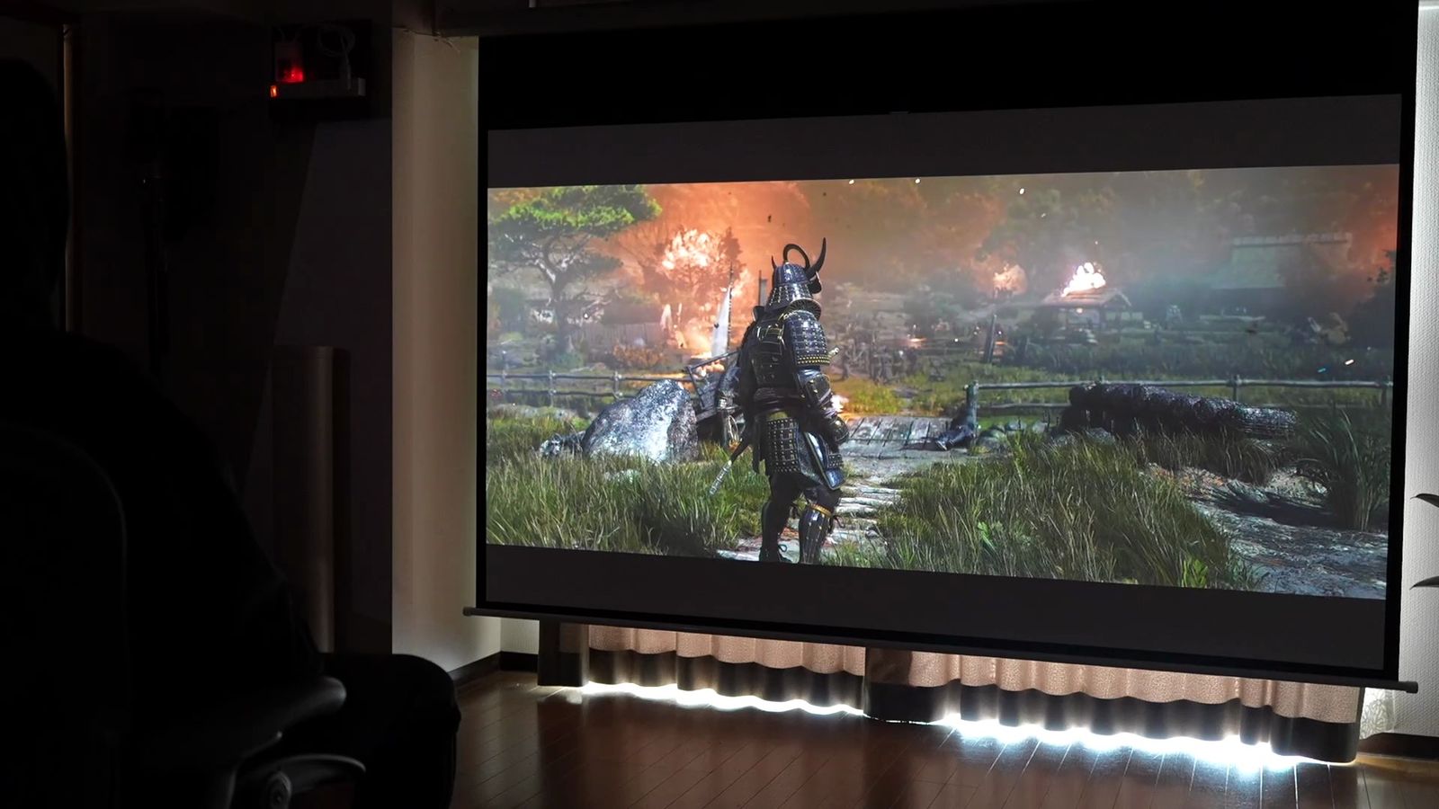 暗い部屋でスクリーンに投影した、侍が立つゲームの場面