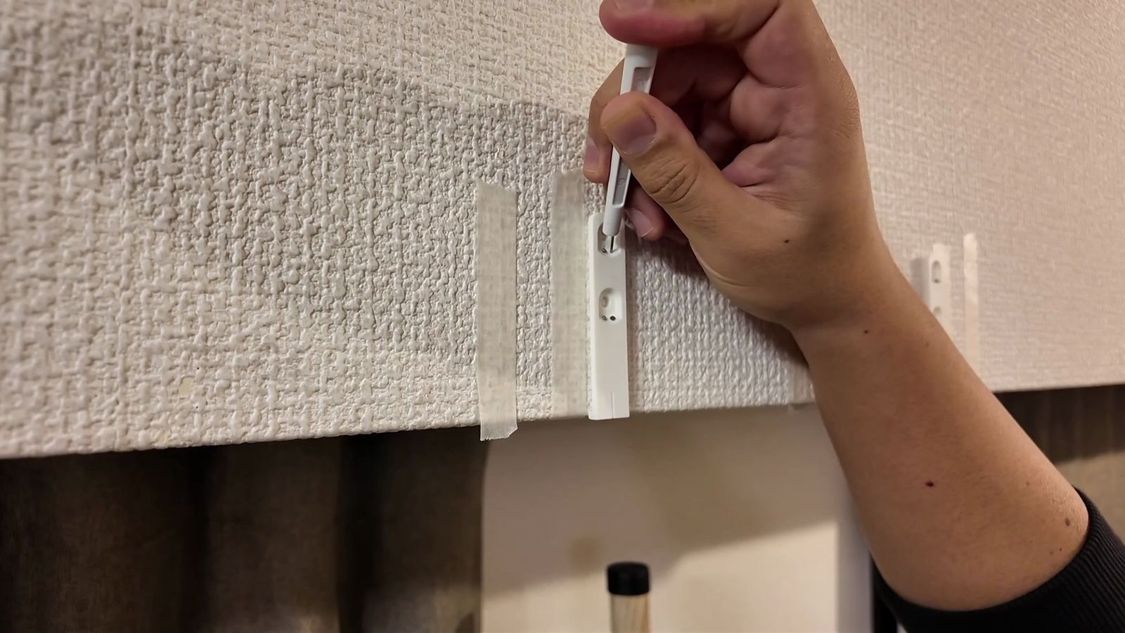 壁に取り付け位置の印を付ける様子