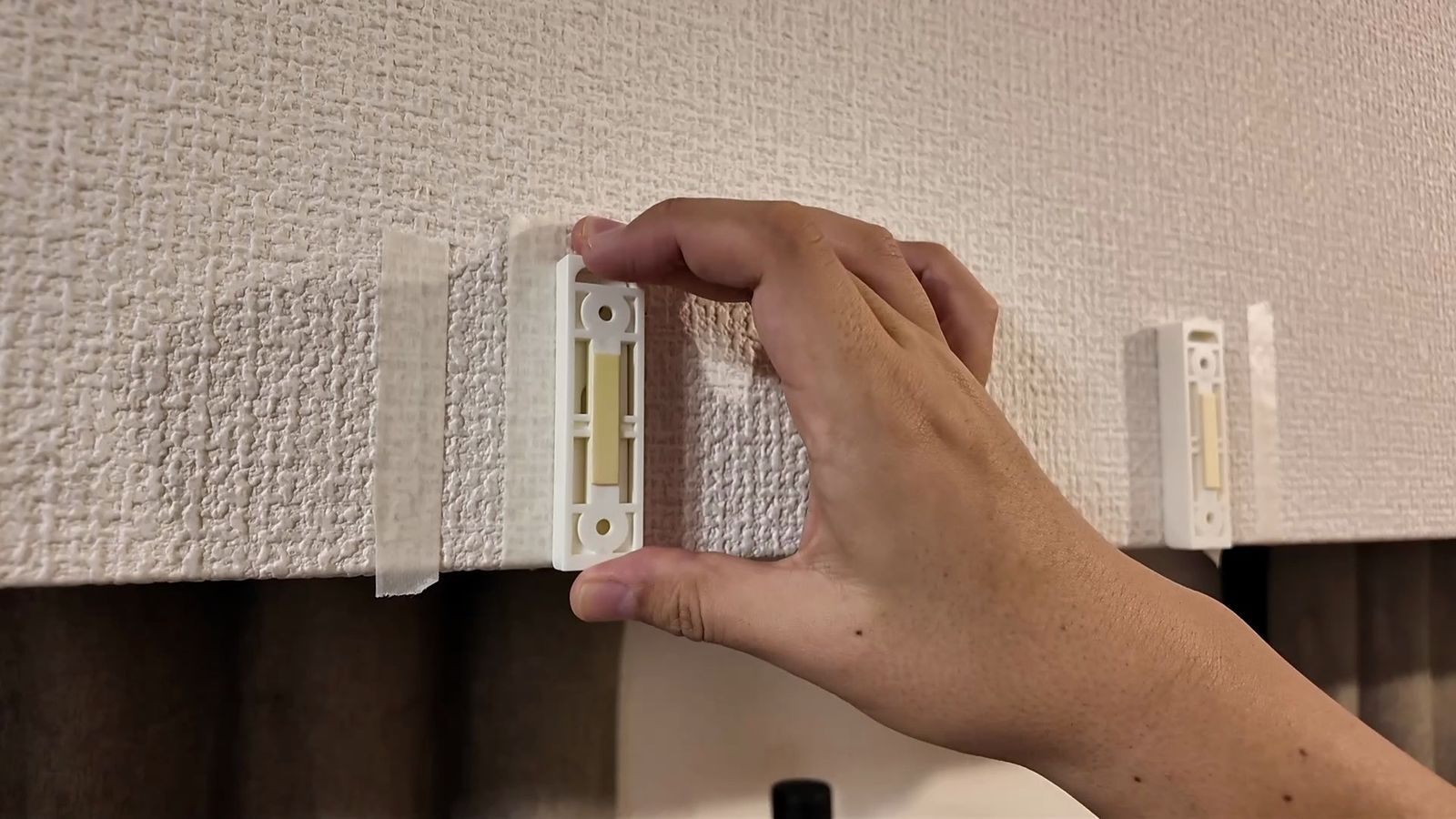 壁のフックパーツにホルダーを差し込む様子