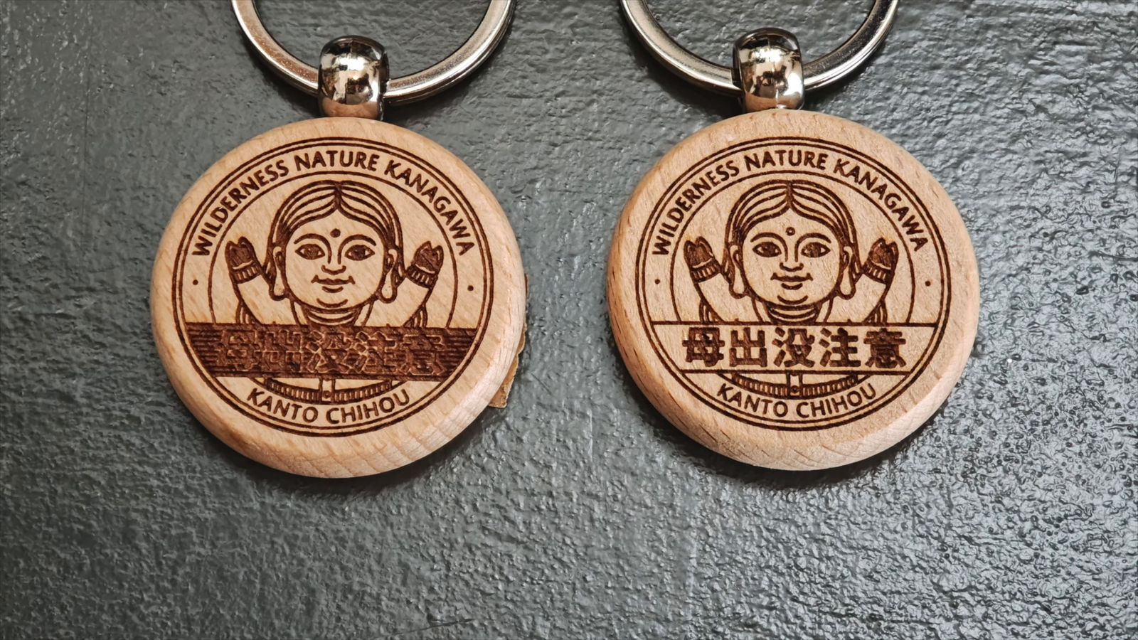 文字の背景のデザインを変えた丸い木のキーホルダー2つ