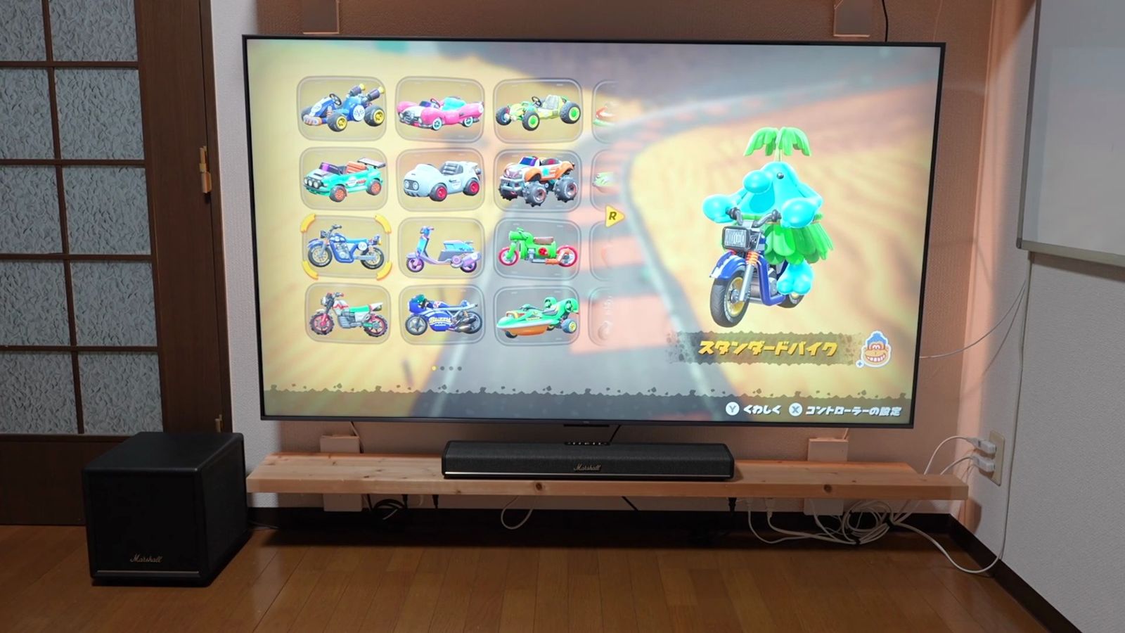 テレビの前にサウンドバー、左にサブウーファーを置いたリビング。テレビにはゲームの画面