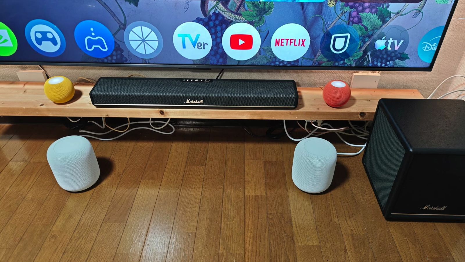 テレビの前のサウンドバーと、床に置いた2台のHomePodとサブウーファー