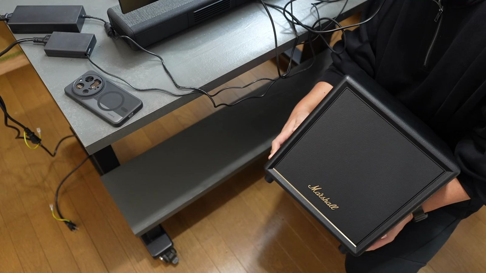デスクの下の棚にサブウーファーを差し込んでいるところ