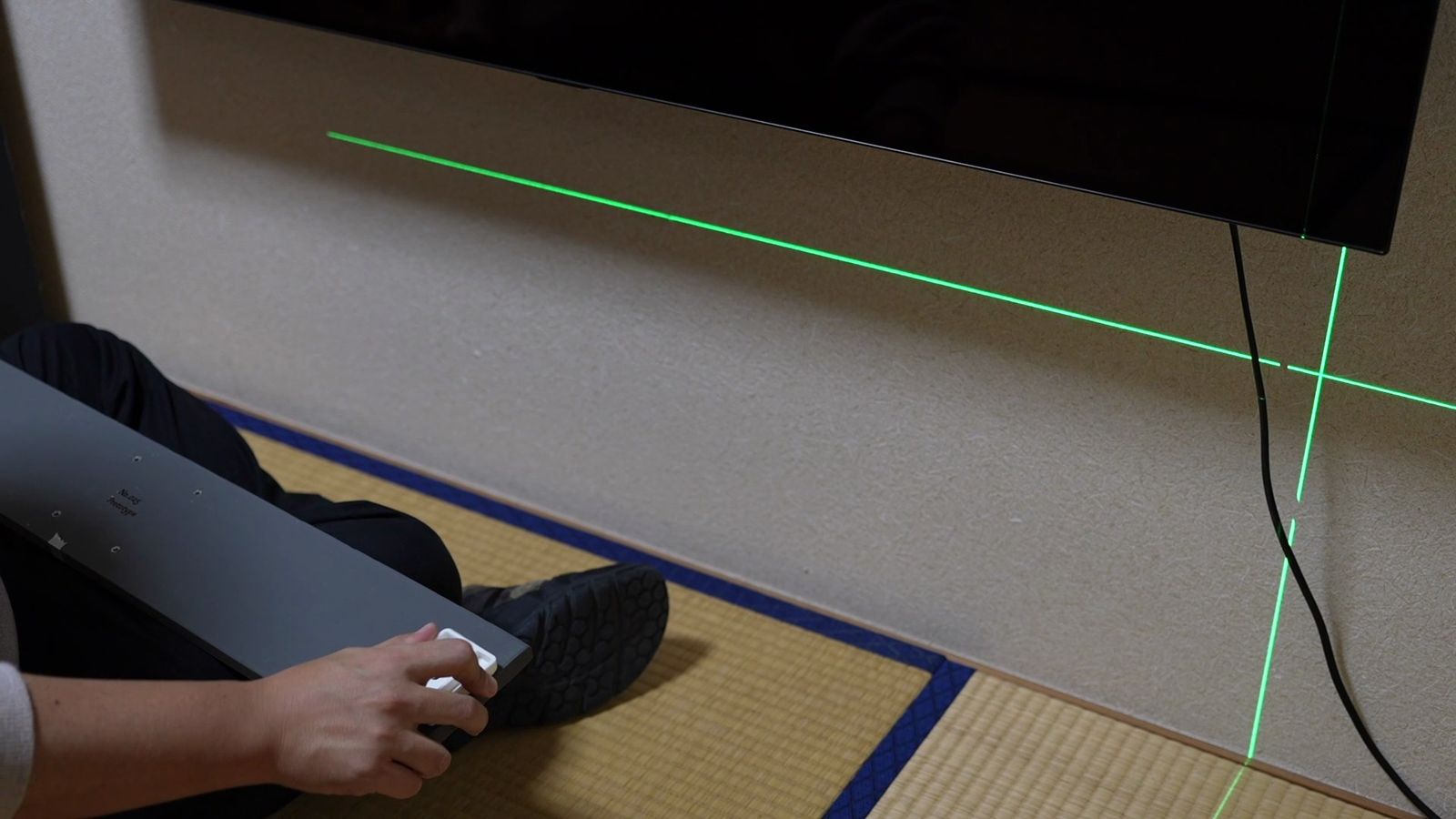 レーザーの線に合わせて、板を壁に押し当てているところ
