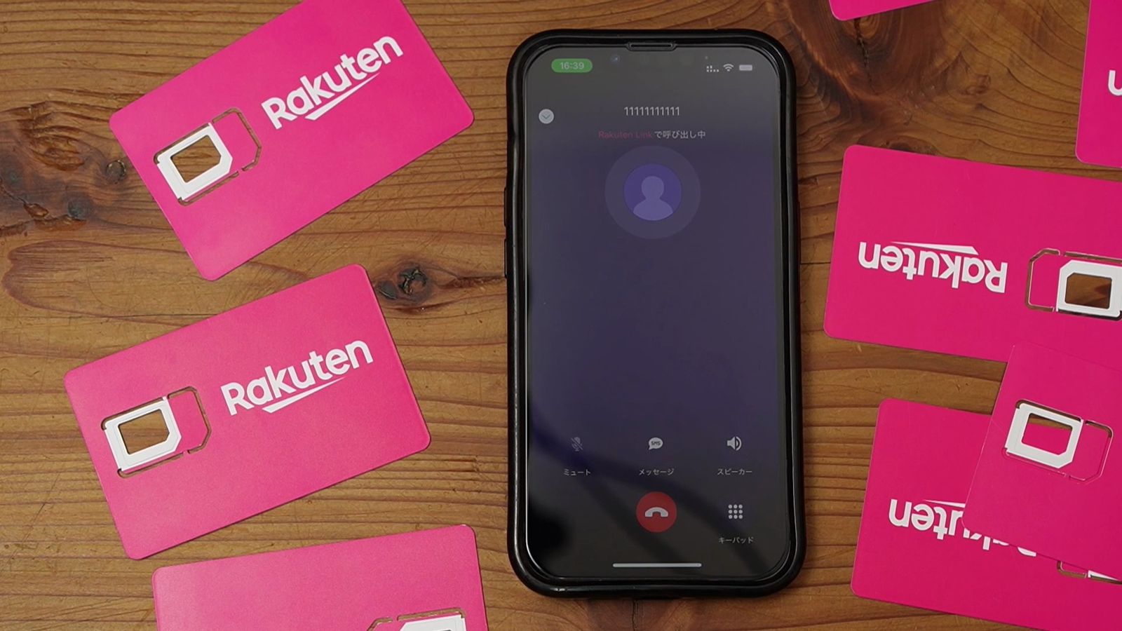楽天モバイルのSIMカードの横に置いたiPhone。Rakuten Linkで呼び出し中の画面