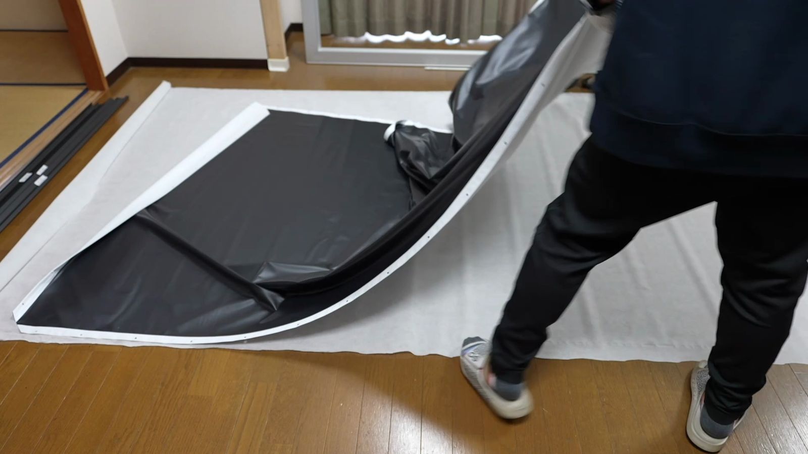 床の保護シートの上に黒い生地を広げているところ
