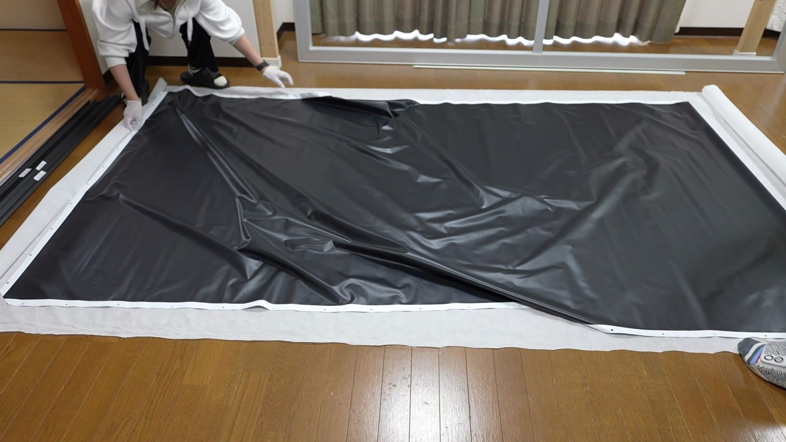 床に広げた黒いスクリーンの生地。シワが寄っている
