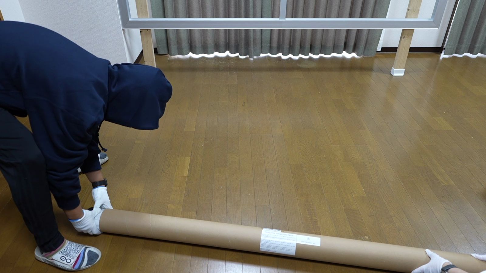 筒に巻かれた生地を床に広げ始めたところ