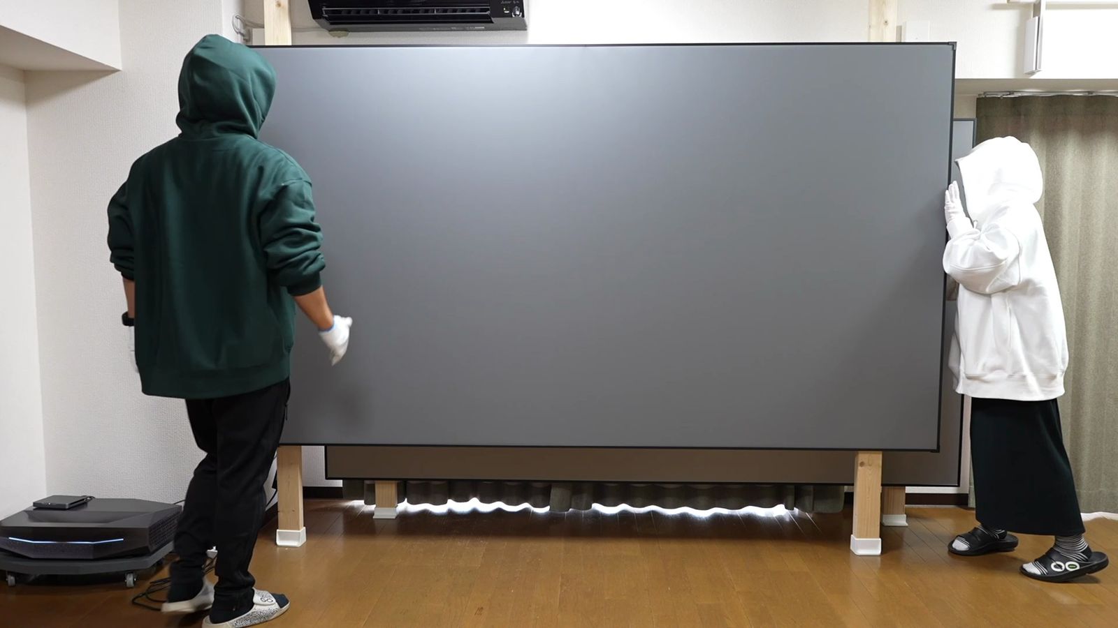 2人で柱にグレーのスクリーンを掛けているところ