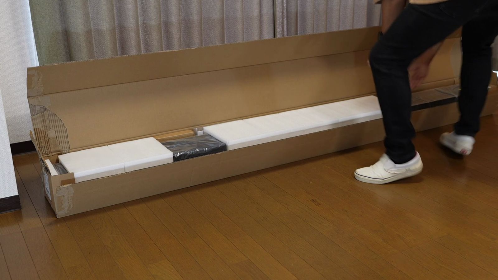 細長い箱からポップアップスクリーンの本体を取り出しているところ