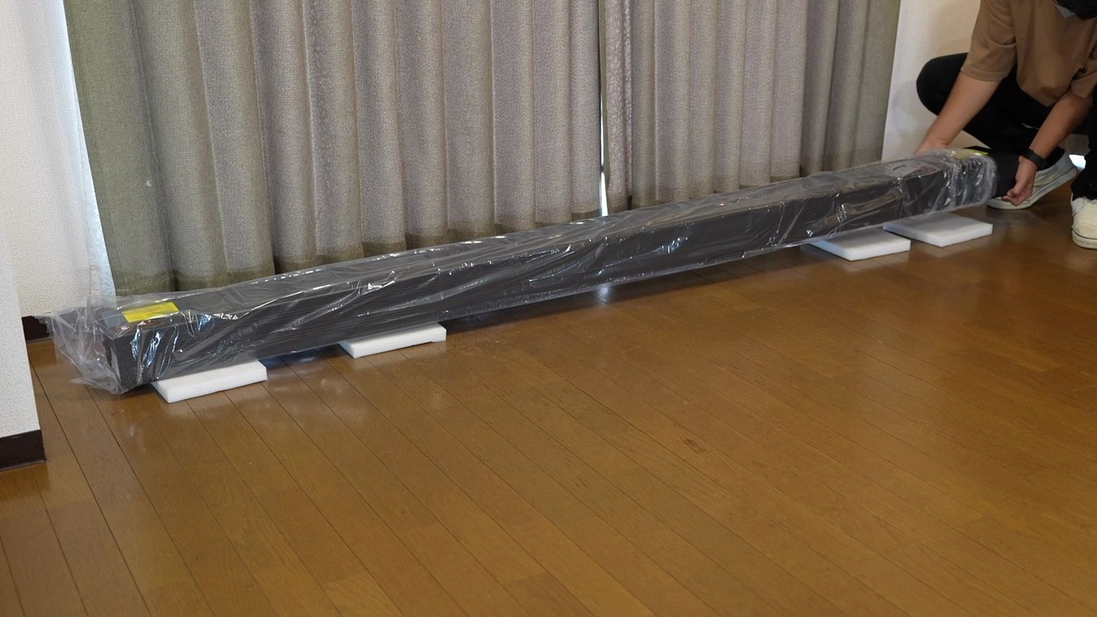 床に置いた、ビニールで包まれた長い本体