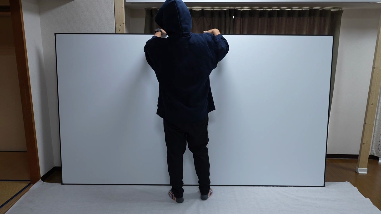 白いスクリーンを一人で持ち上げているところ